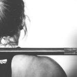 Frau beim schweren Training mit Hantel im Nacken