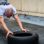 Mann trainiert am Reifen für seinen perfekten Sommerbody